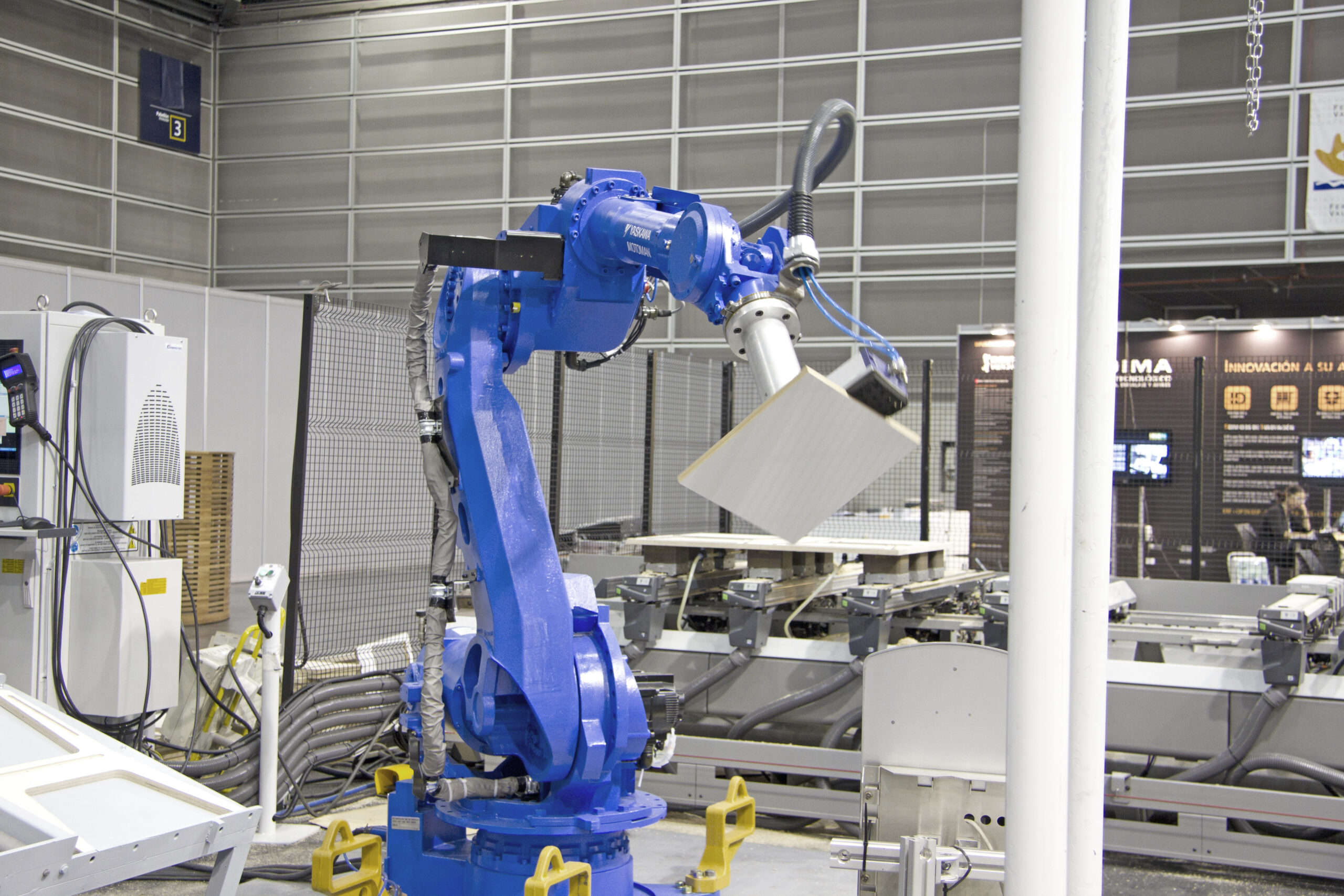 Robot manipulador Yaskawa con garra de ventosas cargando una puerta de madera en un centro de mecanizado